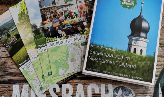 Geheime Plätze im Miesbacher Oberland mit ausgebreiteten Karten über einem Miesbach Schriftzug, © Kulturamt der Stadt Miesbach