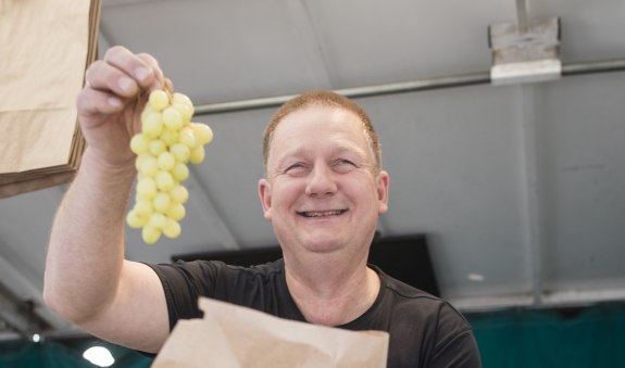 Steffen Schneider steht mit Weintrauben an seinem Stand, © Florian Bachmeier