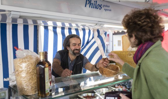 Herr Bahrami bedient eine Kundin an seinem Marktstand, © Florian Bachmeier